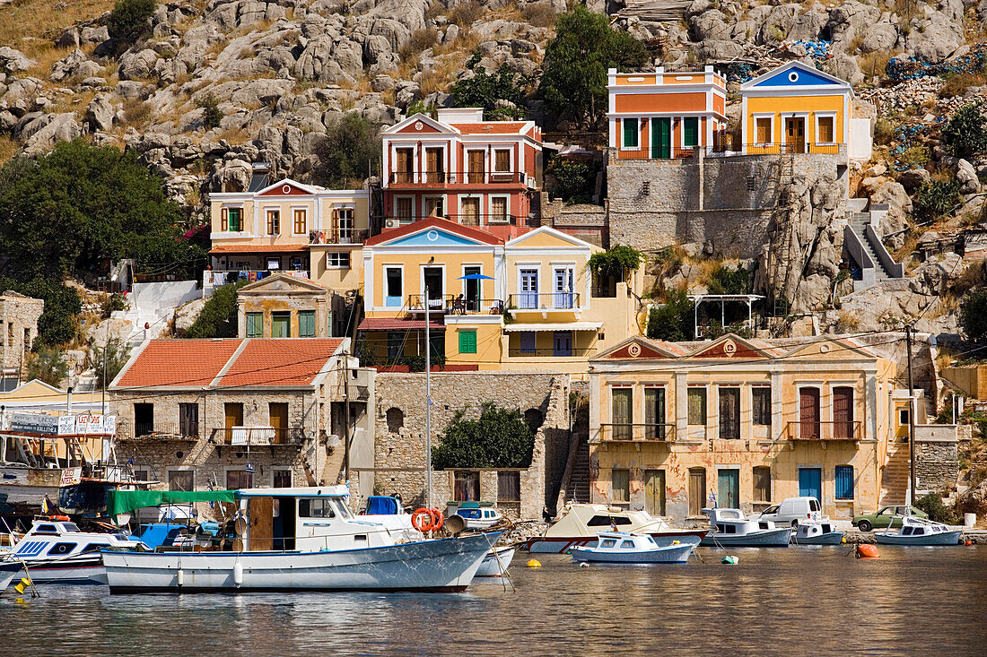 Fishing boats and rowboats anchoring in harbour Gialos, picturesque houses in background, Simi, Symi Island, Greece