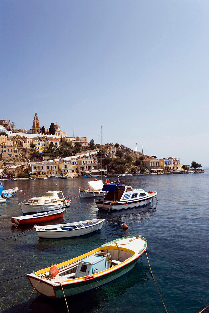 Rowboats and motorboats anchoring in harbour Gialos, view to monastery Moni Evangelismos, Simi, Symi Island, Greece