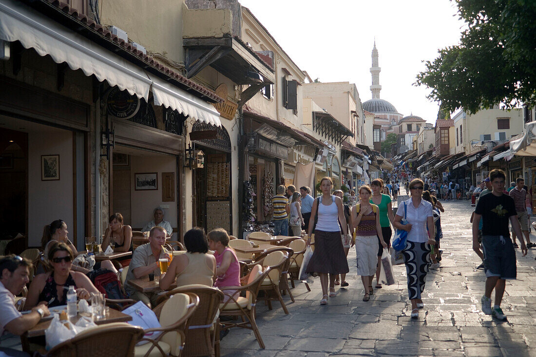 People strolling along shopping street Odos Sokratous, passing a pavement cafe, Rhodes Town, Rhodes, Greece, (Since 1988 part of the UNESCO World Heritage Site)