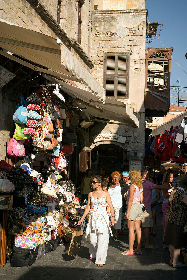 Women passing souvenir shops at Platia Martyrion Evreon (Square of the Hebrew Martyrs), Rhodes Town, Rhodes, Greece (Since 1988 part of the UNESCO World Heritage Site)