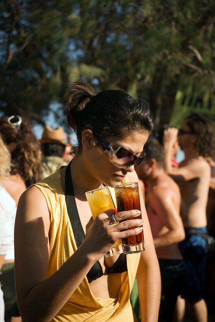 Young woman wearing sunglasses holding drinks, sunday party at Sundance Beach Bar, Gennadi beach, Gennadi, Rhodes, Greece