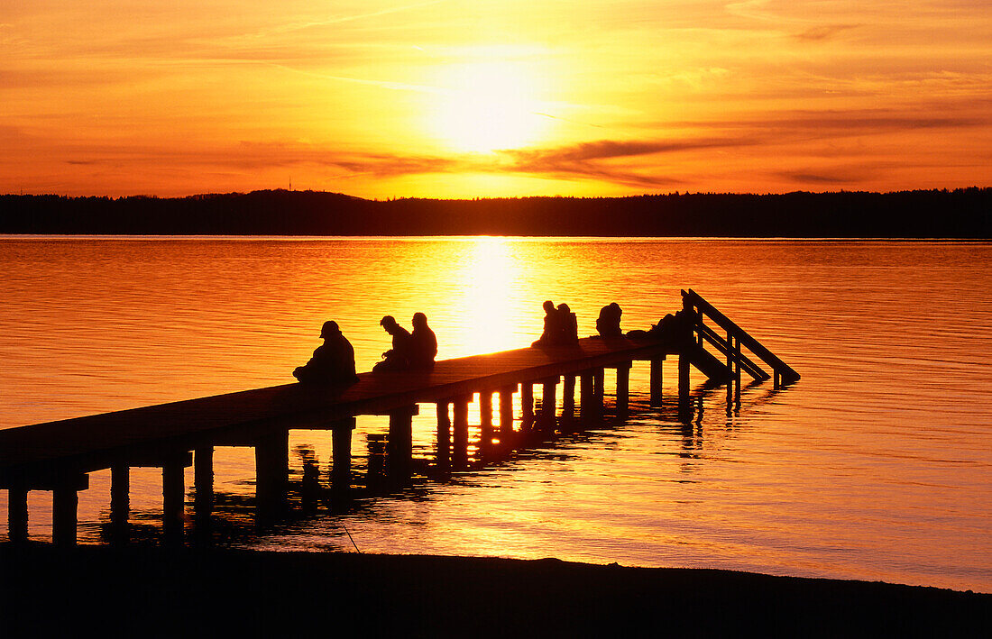People on jetty at Lake Starnberg in sunset, St. Heinrich, Upper Bavaria, Bavaria, Germany