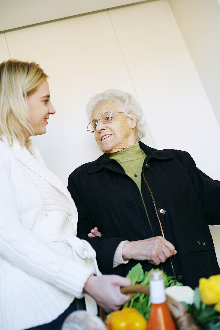 Young woman helps an elderly lady and carries the shopping