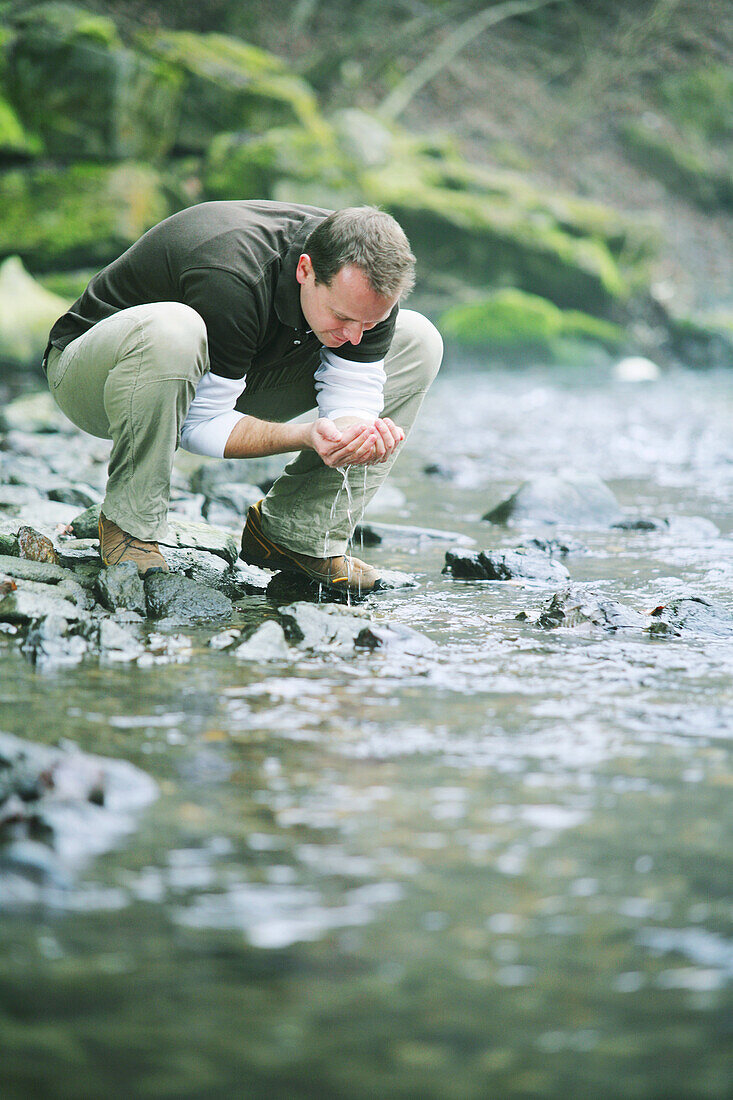 Man drinking water from a stream