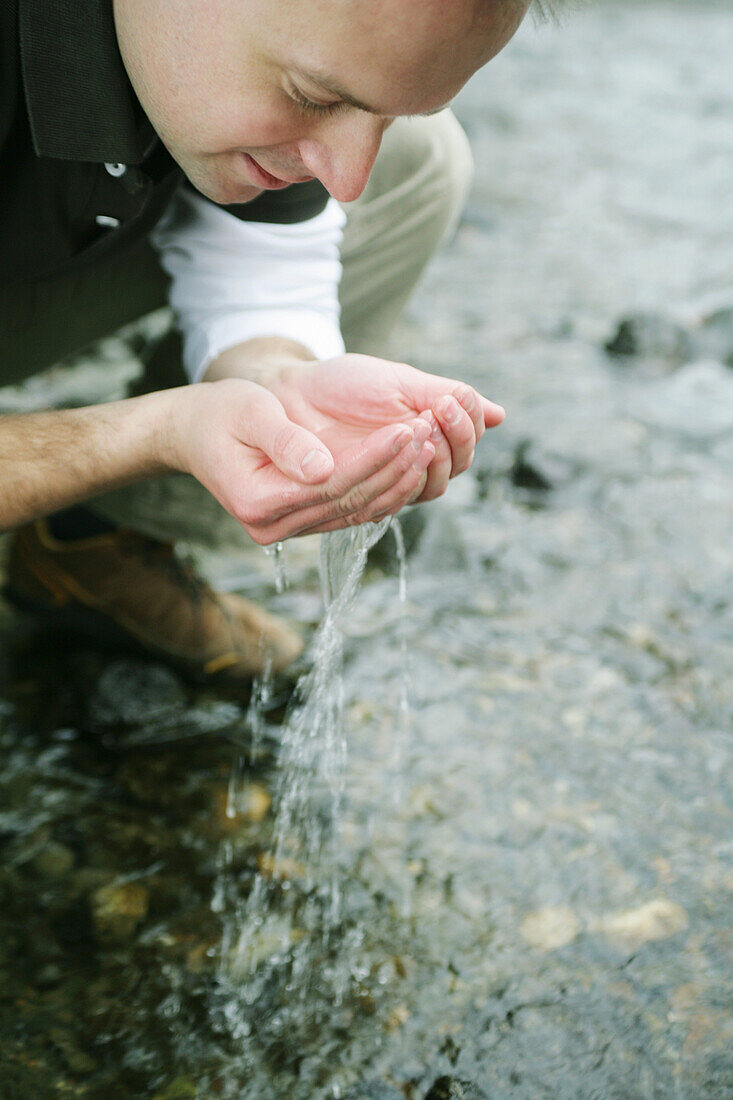 Mann trinkt Wasser am Fluß, Wellness, Natur, Gesundheit