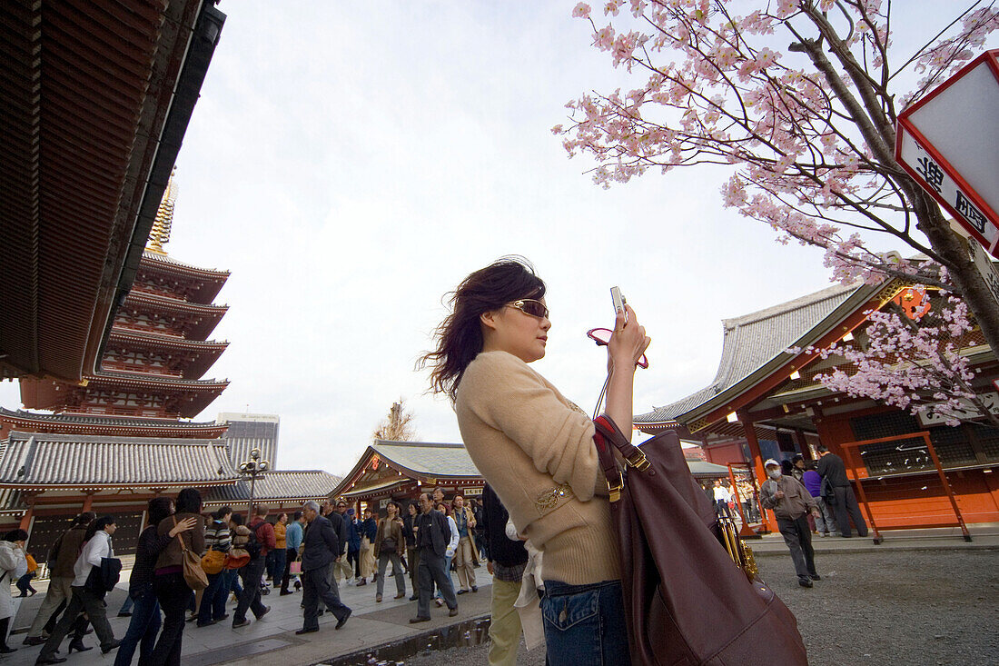 Woman with mobile in front of Asakusa Temple, Tokyo, Japan