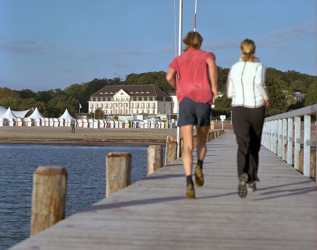Joggers on the jetty in the morning, beach in front of the Spa Hotel Arosa, Travemuende, Schleswig-Holstein, Germany