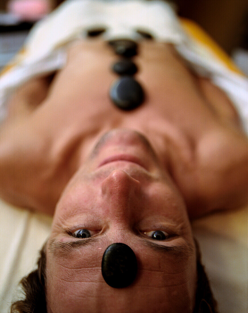 Mann genießt eine Warmsteinmassage mit La-Stone, Deutschland