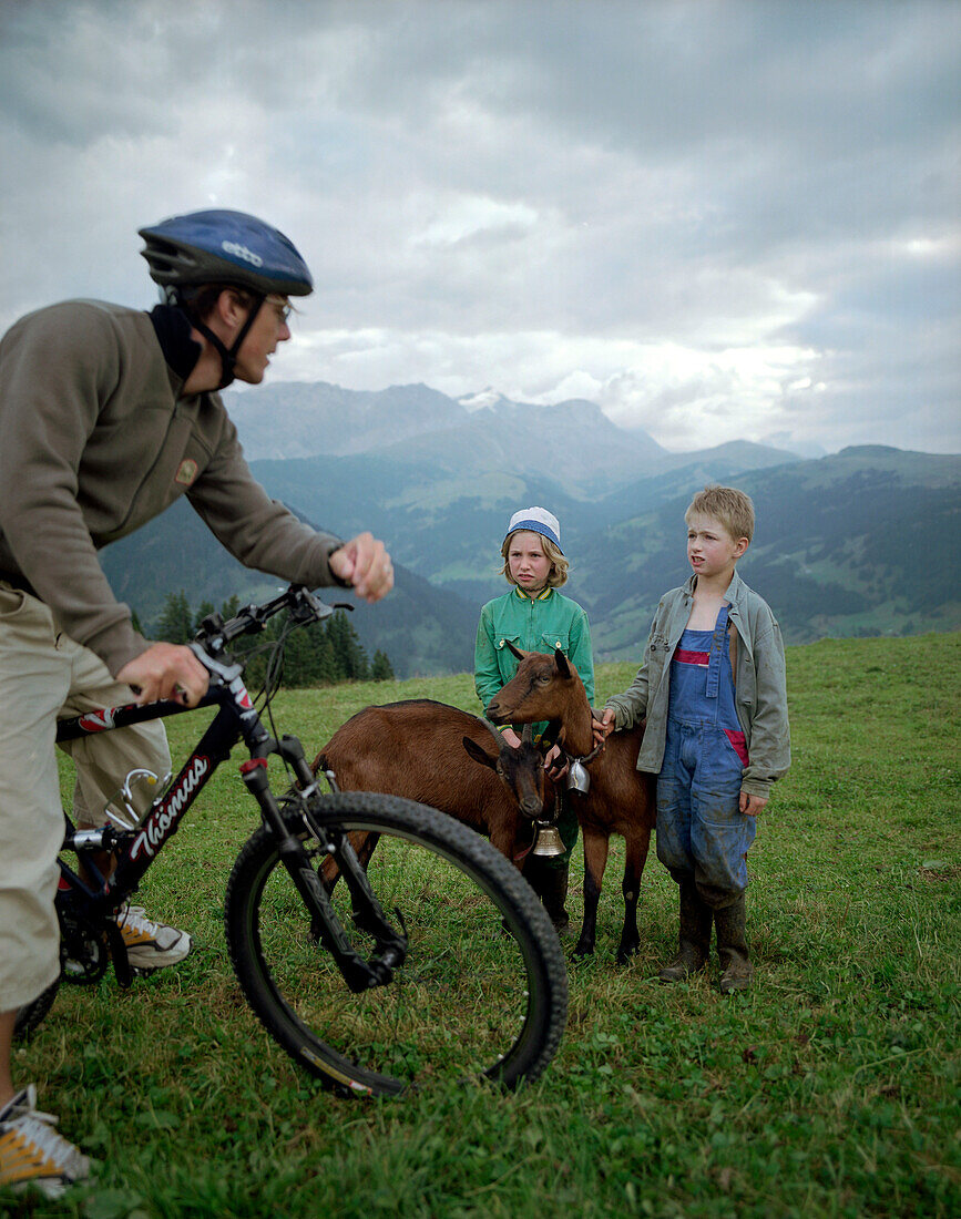 Mountenbiker, children guarding goats, over Simmervallley, near Lenk, Berner Alpen, Kanton Bern, Switzerland