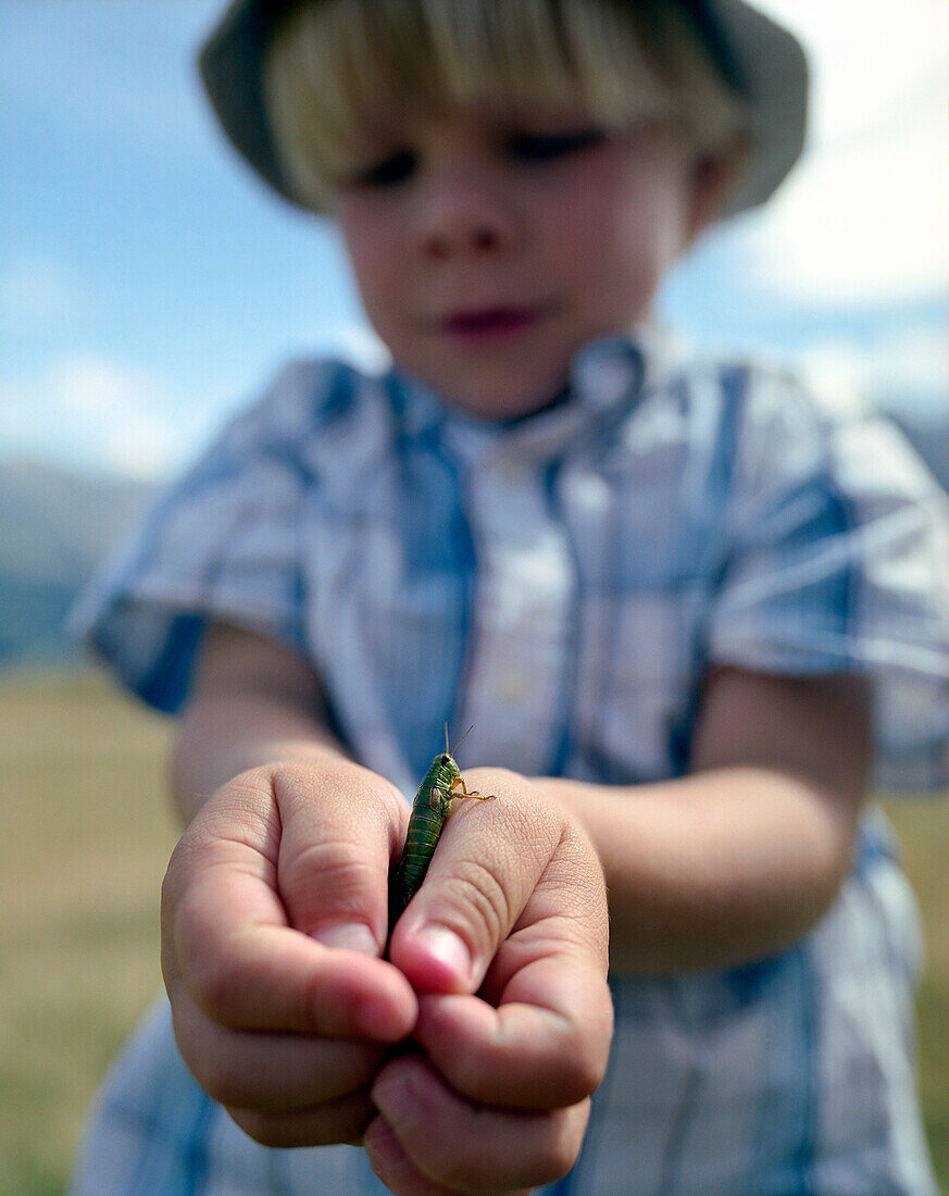 Boy with grasshopper between hands, Simmental vallley, Bernese Alps, Canto of Bern, Switzerland