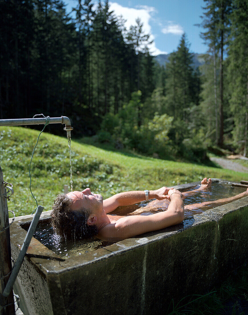 Man bathing in a watering tank, Simmental valley, Bernese Alps, Canton Bern, Switzerland