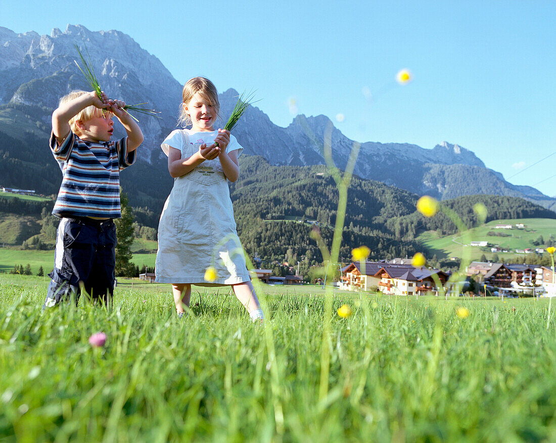 Mädchen und Junge spielen auf einer Wiese, Leogang, Salzburg, Österreich