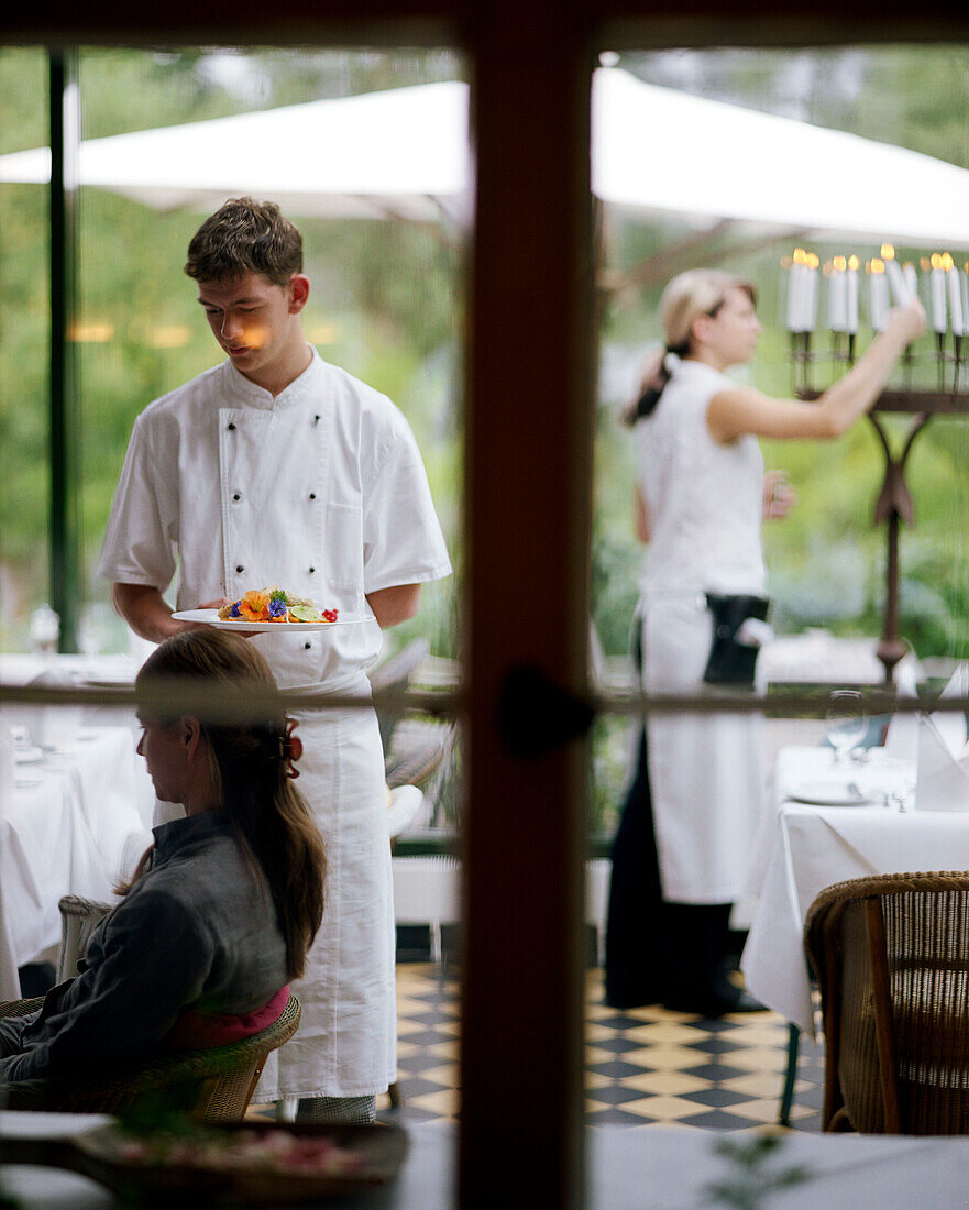 Cook serves a dinner, at the terrace of the spa hotel Seehotel Neuklostersee, Mecklenburg - Western Pomerania, germany