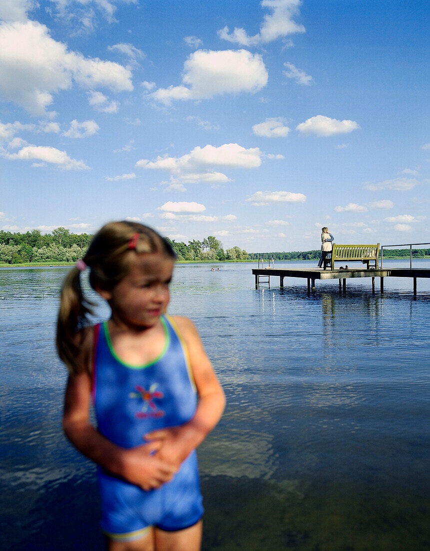 Girl (5 years) standing at lakeshore, Lake Neukloster, Nakenstrof, Mecklenburg-Western Pomerania, Germany