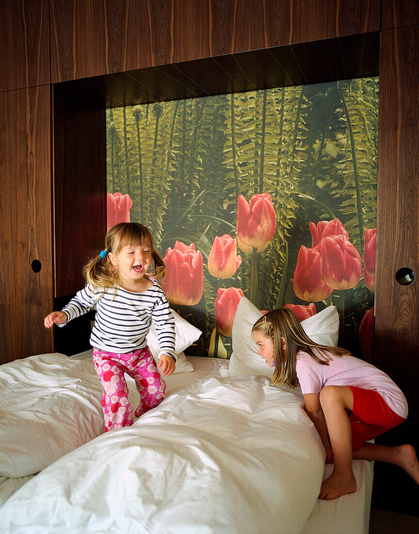 Zwei Mädchen hüpfen auf Bett, Gästezimmer, Fototapete, Wellnesshotel, Seehotel Neuklostersee, Mecklenburg-Vorpommern, Deutschland