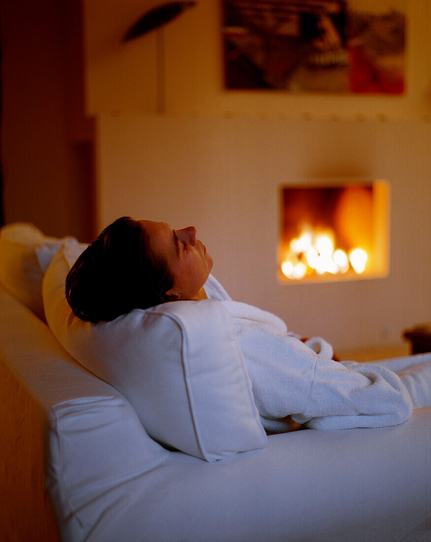 Woman relaxing near an open fire place, relaxation room, Spa Area of Seehotel Neuklostersee, Mecklenburg - Western Pomerania, Germany