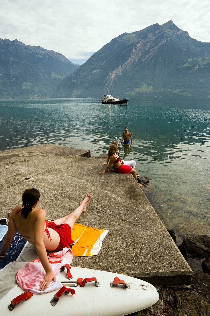 Girls sunbathing on rock, Lake Urnersee, part of Lake Lucerne, Bauen, Canton of Uri, Switzerland