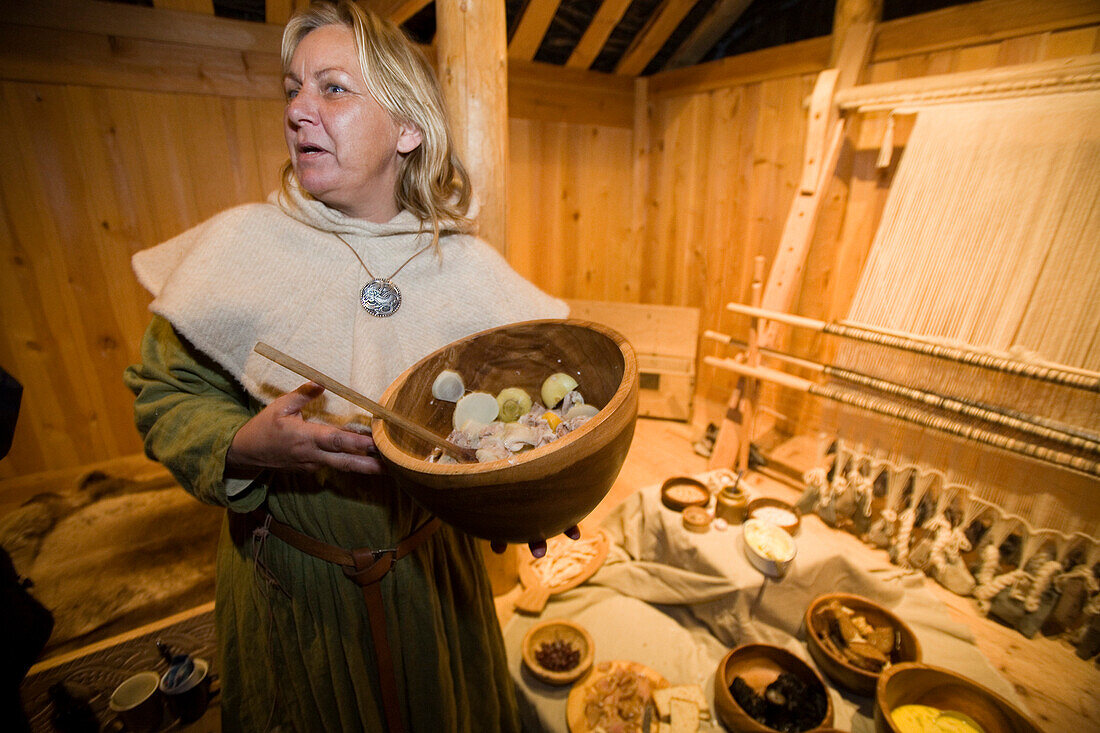 A woman serves a viking meal in a reconstructed longhouse at Qassiarsuk. the place were the first vikings with Erik the Red settled. South Greenland.
