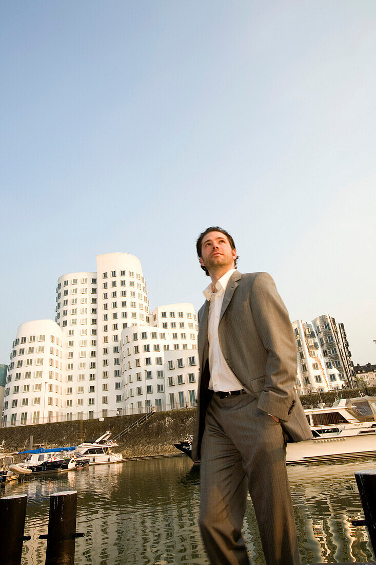 Vorbeigehender junger Geschäftsmann, Neuer Zollhof, Architektur von Frank O.Gehry, Medienhafen in Düsseldorf, Nordrhein-Westfalen, Landeshauptstadt in NRW, Deutschland