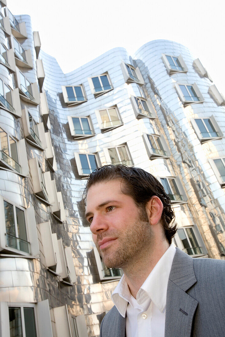 Young business man in front of Neuer Zollhof, modern architecture from Frank Gehry, Media Harbour, Düsseldorf, state capital of NRW, North-Rhine-Westphalia, Germany