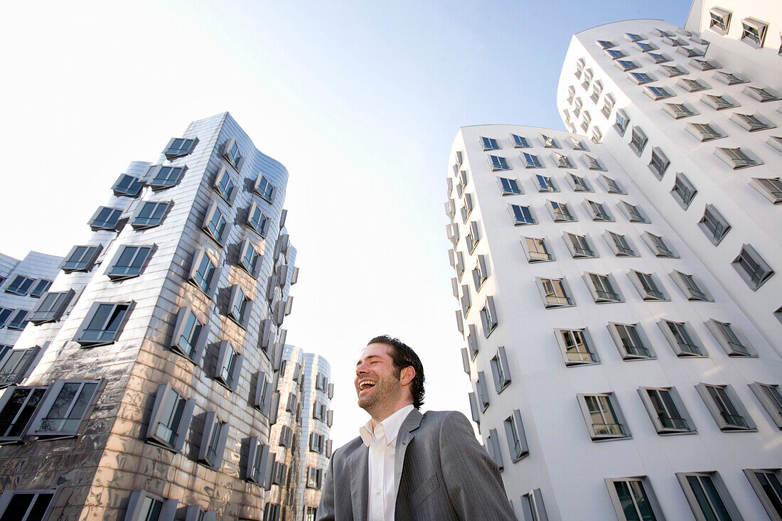 Junger Geschäftsmann vor neuer Zollhof, Architektur von Frank O.Gehry, Medienhafen in Düsseldorf, Nordrhein-Westfalen, Landeshauptstadt in NRW, Deutschland