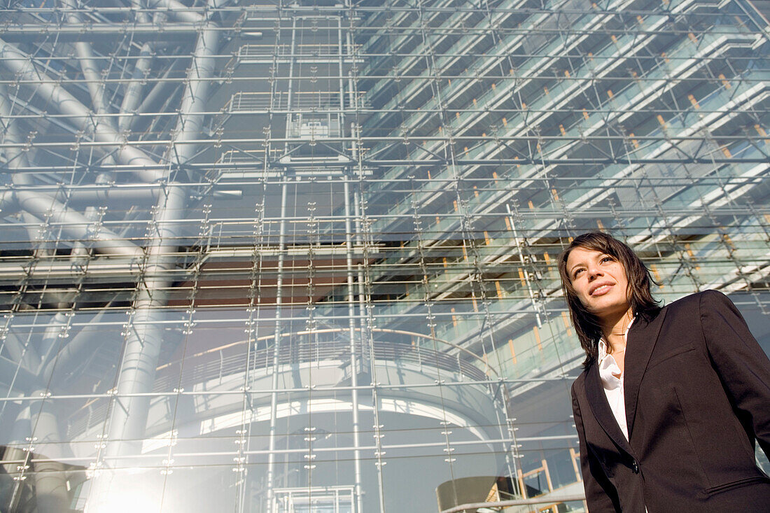 Young business woman in front of a modern office building, Stadttor, Media Harbour Düsseldorf, state capital of NRW, North-Rhine-Westphalia, Germany