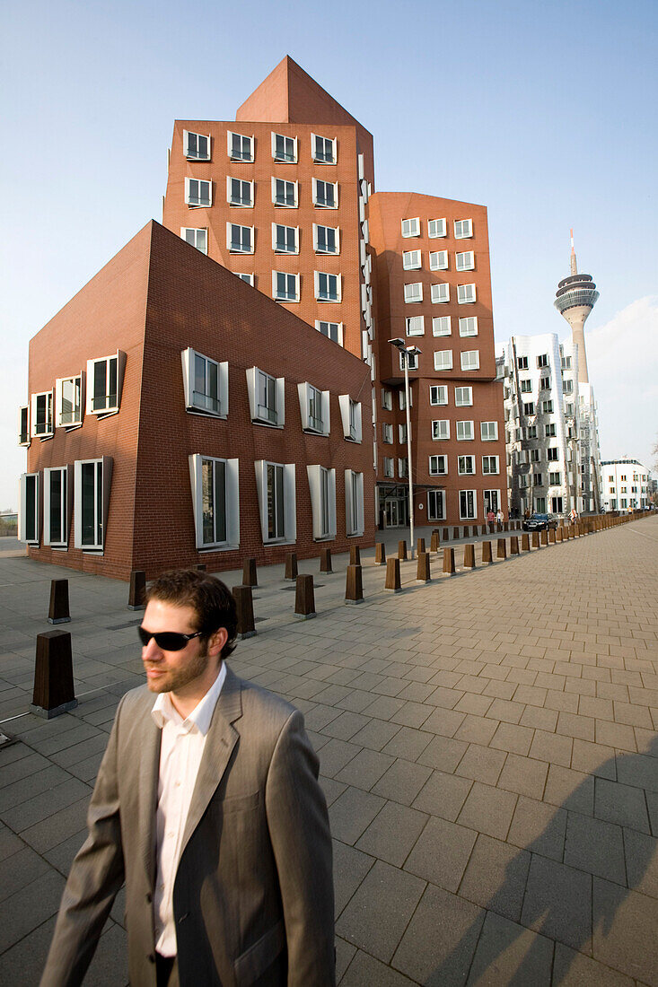 Junger Geschäftsmann vor Neuer Zollhof, Architektur von Frank O.Gehry, Medienhafen in Düsseldorf, Hafenbecken, Nordrhein-Westfalen, Landeshauptstadt in NRW, Deutschland