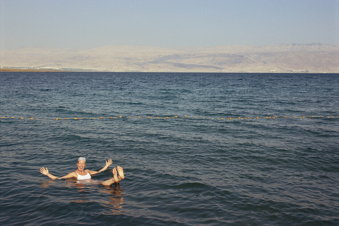 Frau beim Baden im Toten Meer und Jordanien im Hintergrund, Israel