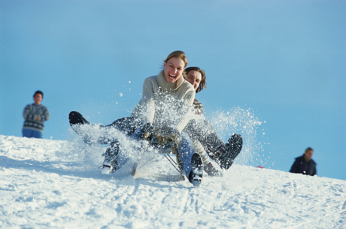 Junges Paar beim Rodeln, Schlittenfahren im Schnee, Oberbayern, Bayern, Deutschland