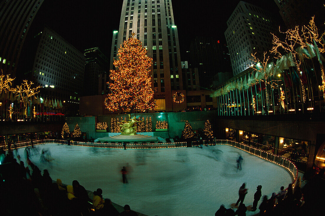 Rockefeller Center at night with Christmas decorations, Lower Plaza with Prometheus, People ice scating in the foreground, New York City, USA
