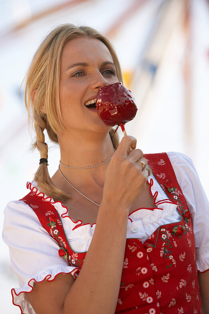 Woman wearing dirndl dress eating candied apple