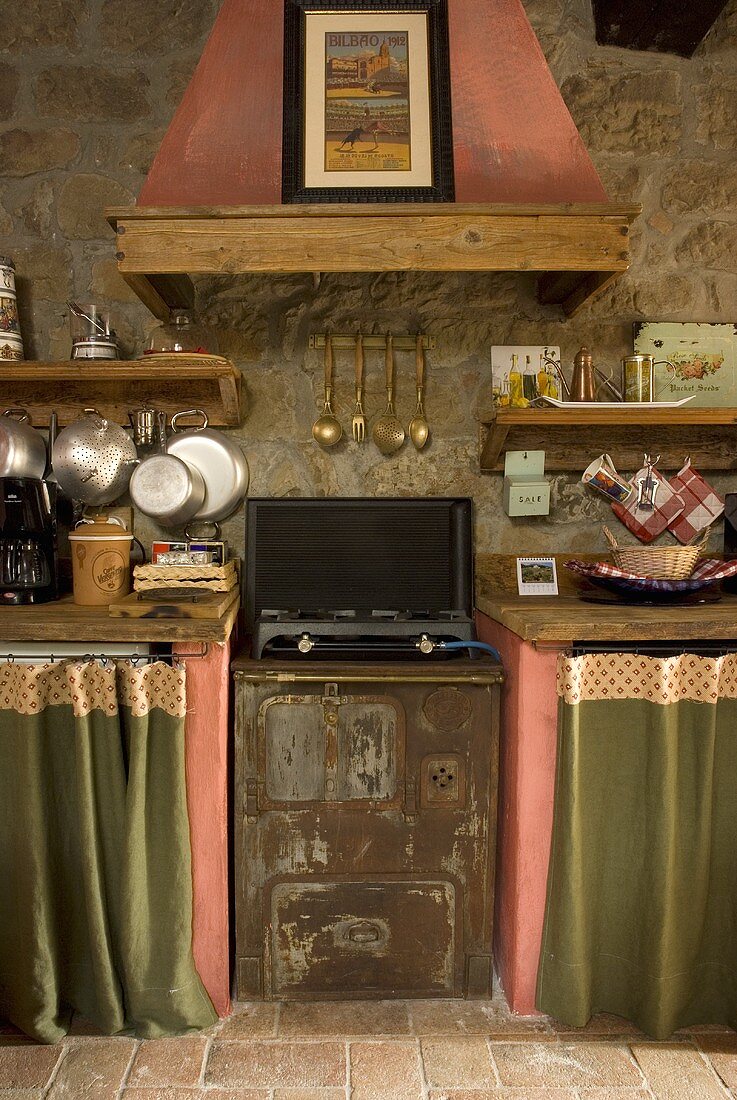 An old-fashioned oven with a brick extractor fan on a natural stone wall