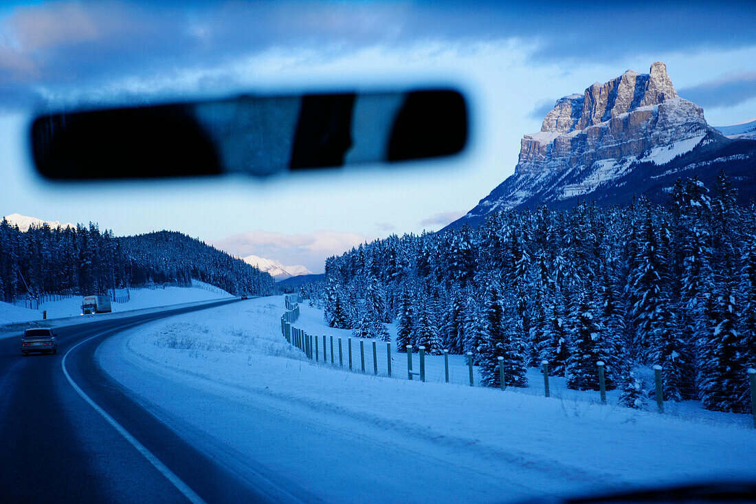 Blick auf verschneiten Highway durch die Windschutzscheibe, in der Nähe von Lake Louise, Alberta, Kanada