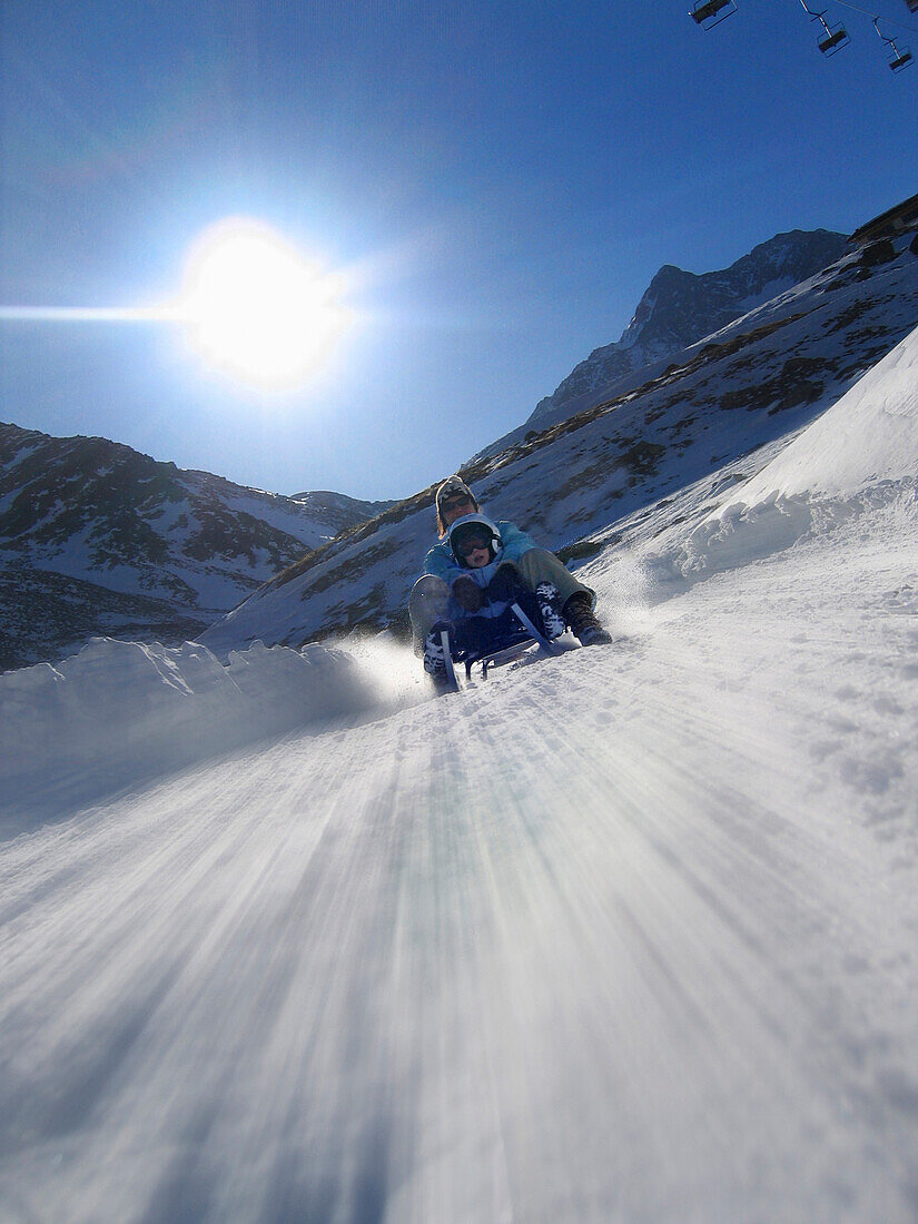 Mutter und Sohn rodeln auf Lazaun Rodelbahn, Schnalstal, Südtirol, Italien, MR