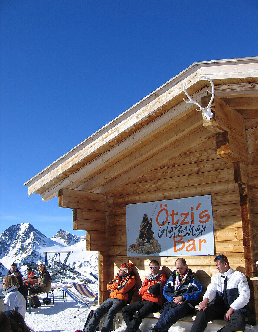 Four people sitting outside an alpine hut, Oetzis Gletscherbar, Schnalstal, South Tyrol, Italy