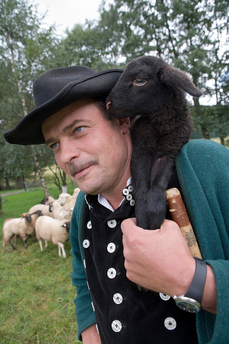 Shepherd with black lamb on his shoulder, Rhoen Sheep, Schaeferei Weckbach, Ehrenberg Wuestensachsen, Rhoen, Hesse, Germany