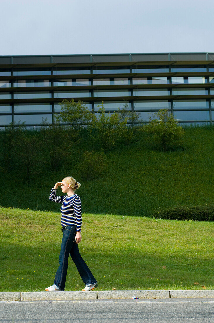 Woman walking past modern building, Luxembourg