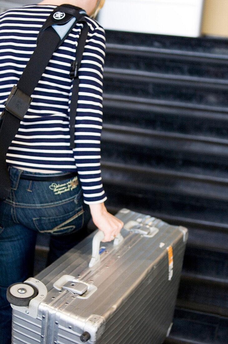 Woman with aluminium suitcase on staircase, airport, Luxemburg