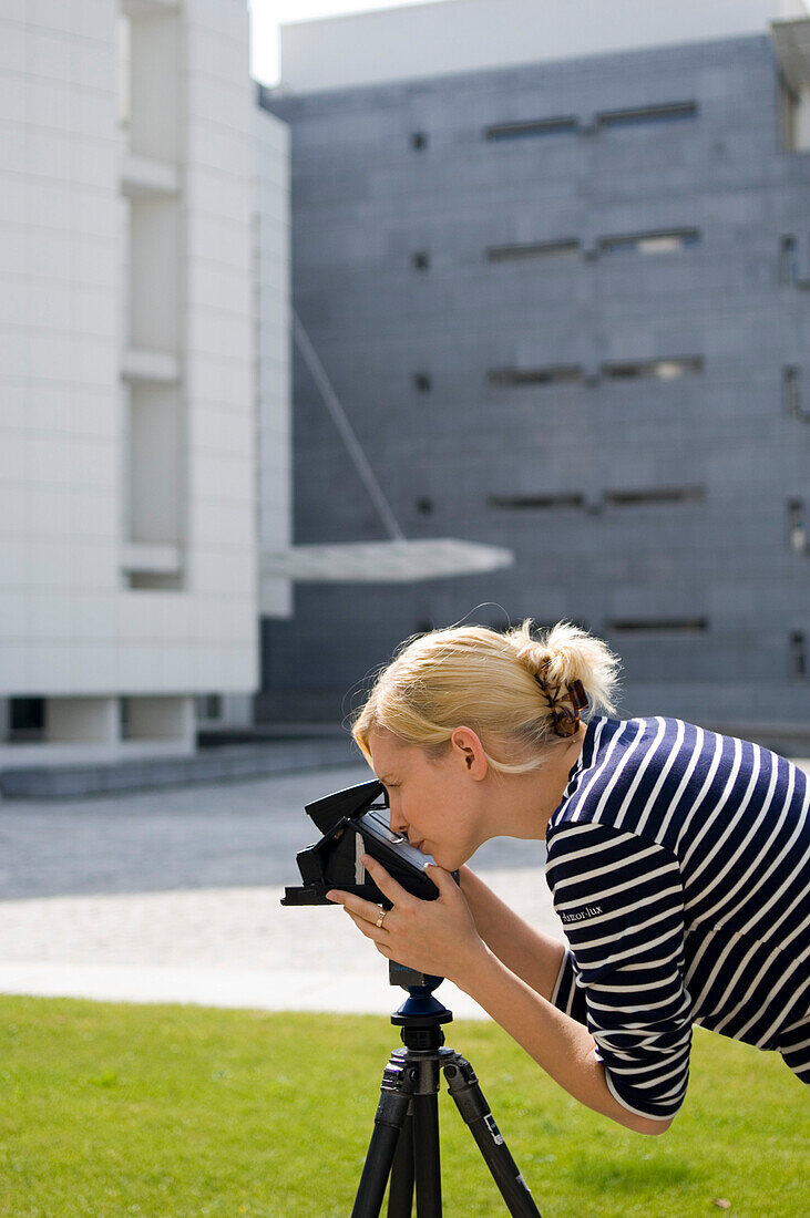 Junge Frau fotografiert mit einer Kamera auf einem Stativ, Luxemburg
