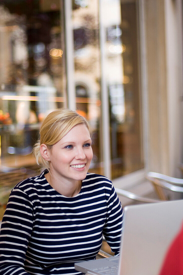 Junge Frau mit Laptop in Café, Luxemburg