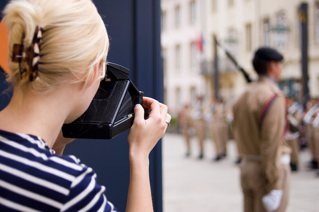 Young woman photographing changing of the guard at Grand Ducal Palace, Luxembourg, Luxembourg