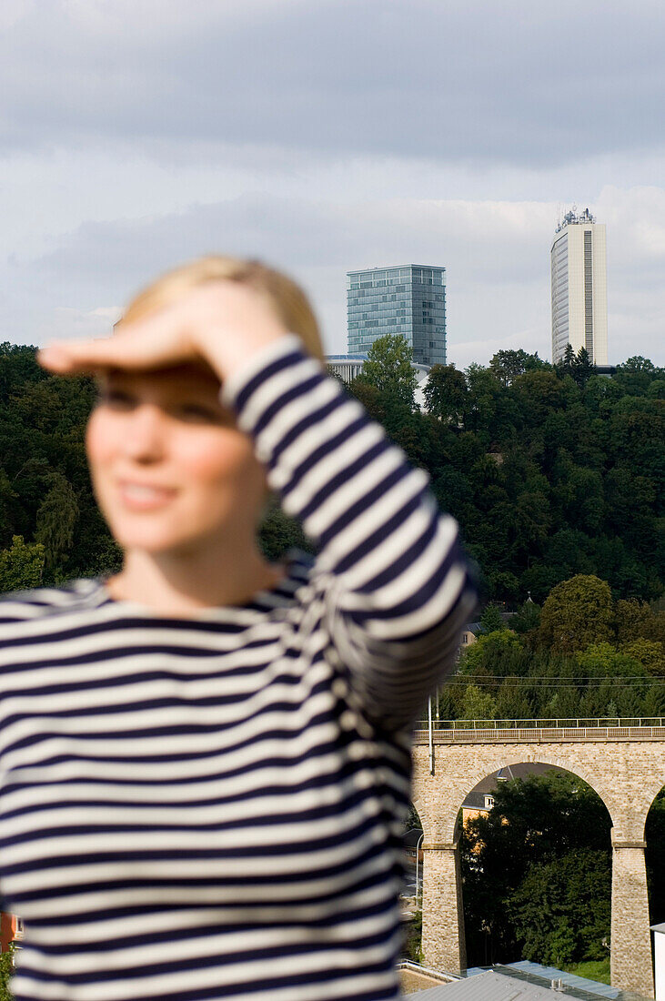 Junge Frau blickt in die Ferne, Hochhäuser im Hintergrund, Luxemburg, Luxemburg