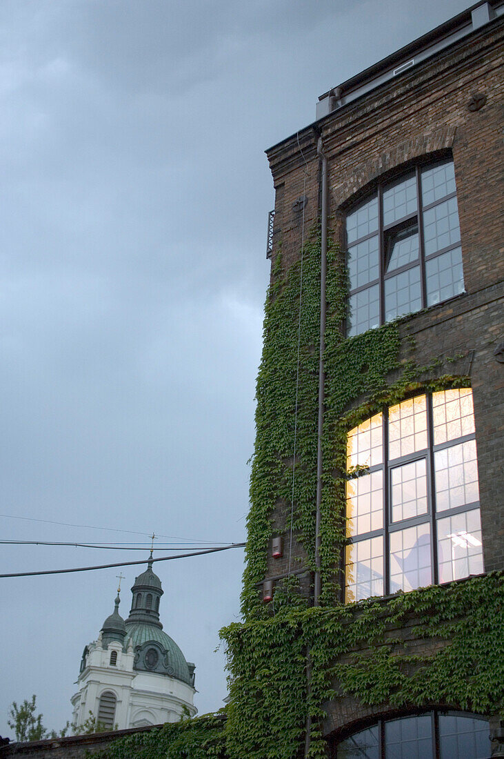 Erleuchtetes Fenster eines Hauses und Kirchturm am Abend, Warschau, Polen