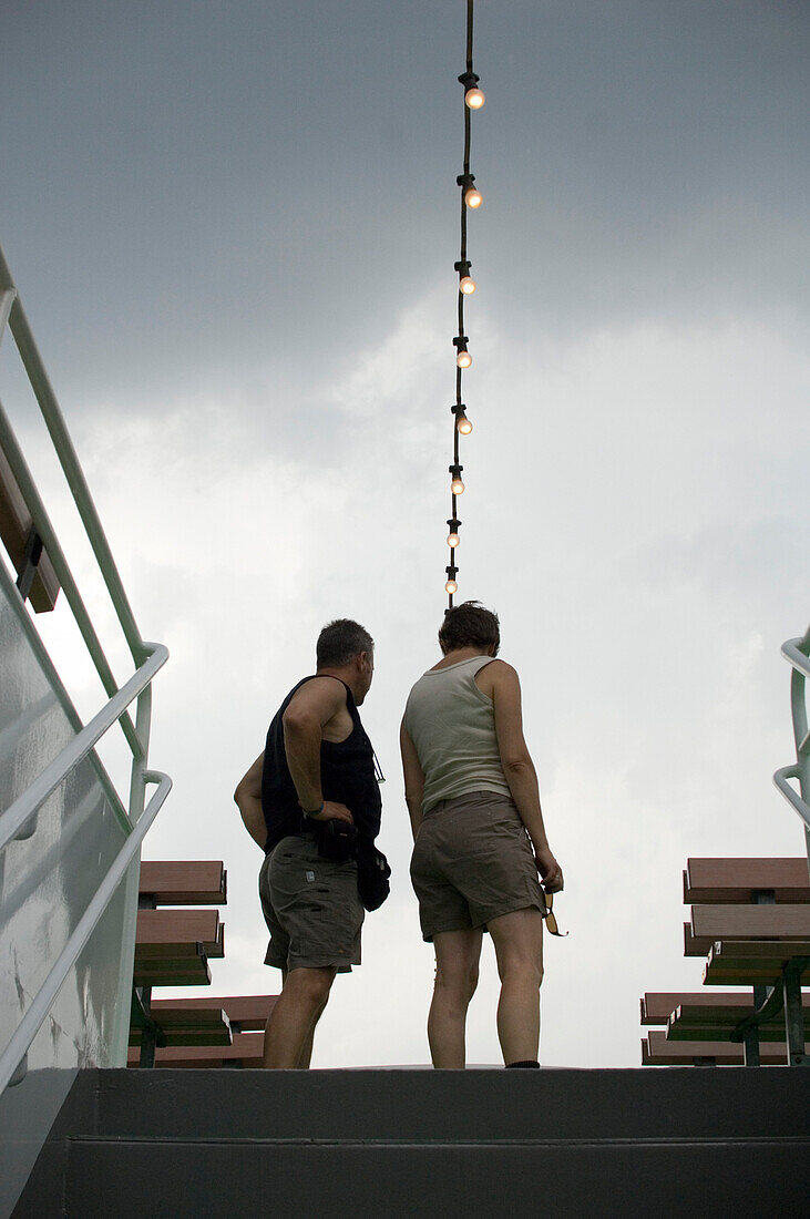 People on excursion boat under dark clouds, Traben-Trarbach, Moselle, Rhineland-Palatinate, Germany