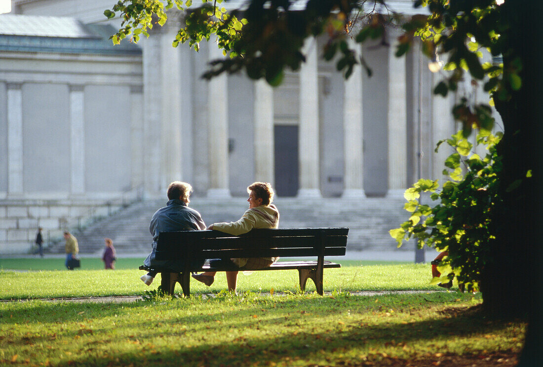 Mature couple sitting on a bench at Koenigsplatz, Munich, Bavaria, Germany