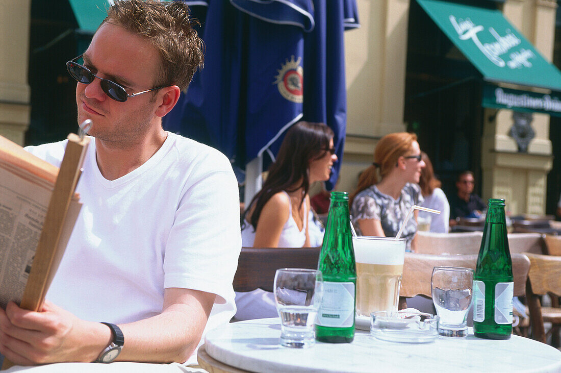 Junger Mann sitzt im Café Tambosi, München, Bayern, Deutschland