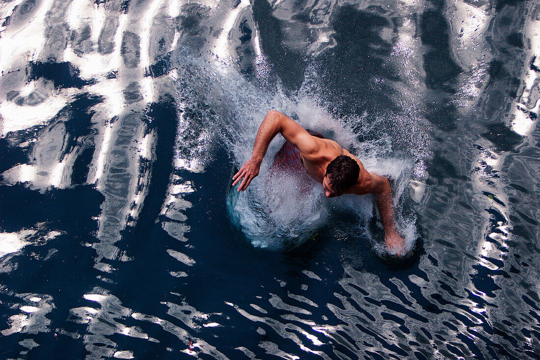 Young man jumping into Lake Alpsee, Schwangau, Bavaria, Germany