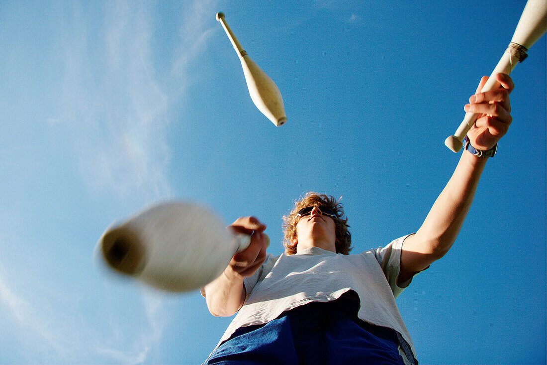 Young man juggling with clubs, Irsee, Bavaria, Germany