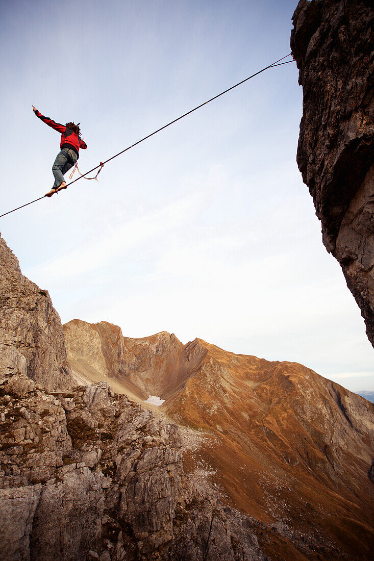 Slackline, Junger Mann balanciert auf einem Seil zwischen zwei Felsen, Oberstdorf, Bayern, Deutschland