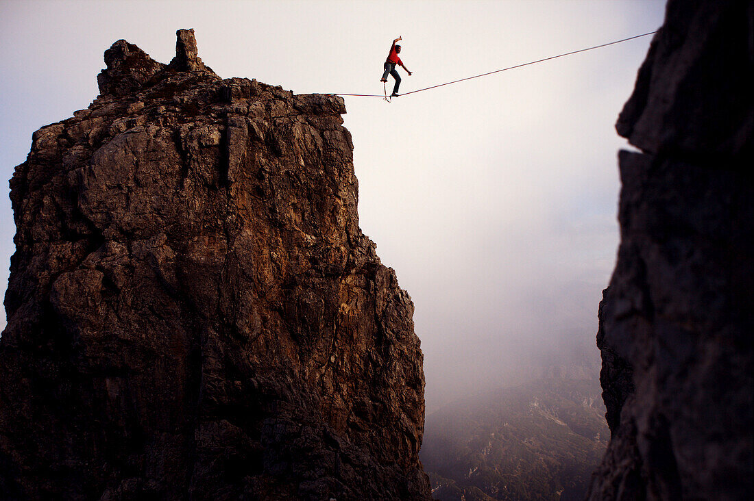 Junger Mann balanciert auf einem Seil zwischen zwei Felsen, Oberstdorf, Bayern, Deutschland